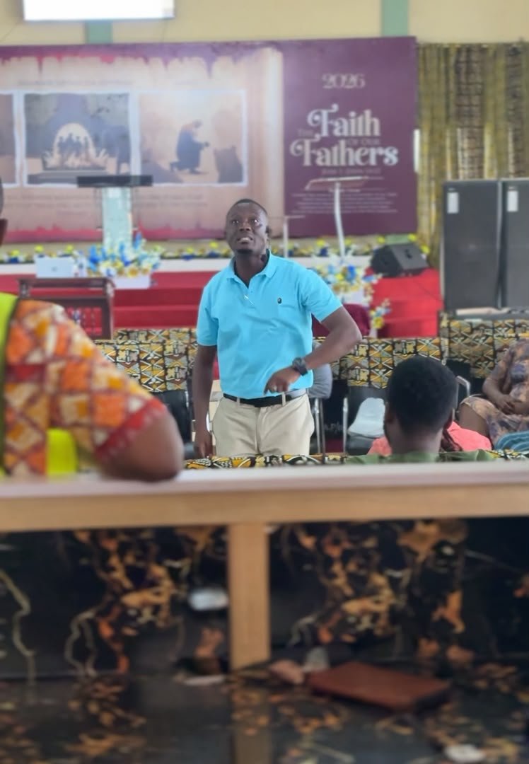 A speaker addressing seated attendees during a church session.